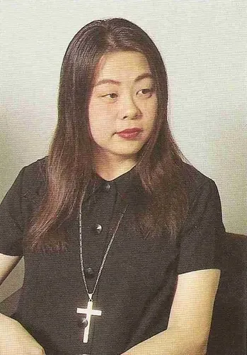 Rieko Kodama sitting, wearing a holy cross necklace.